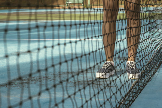 Legs Of Female Tennis Player.Close Up Back Net 