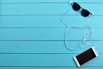cell phone and headphones on a blue wooden table.
