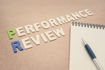 Performance review text with open spiral notebook and pen