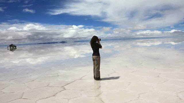 Woman taking pictures in the middle of the lake Salar de Uyuni, Bolivia