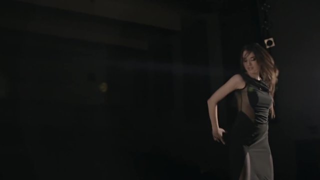 Young woman in black dress dancing under the spotlight