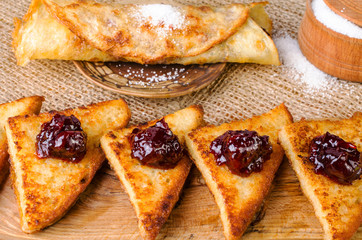 Toast with jam, sugar bowl and pancake on a plate.