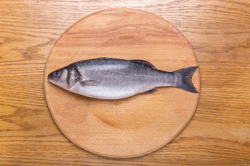 sea bass fish on a wooden board top view