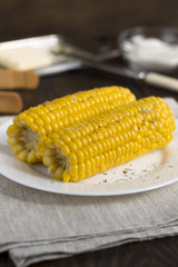 Boiled corn on a plate on the wooden table.