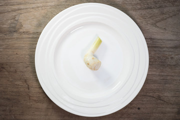 Galangal in ceramic dish on wood background.