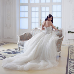 Portrait of beautiful laughing bride. Wedding dress with open back. Luxurious light interior