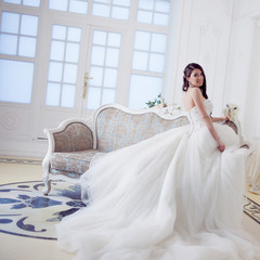 Portrait of beautiful laughing bride. Wedding dress with open back. Luxurious light interior