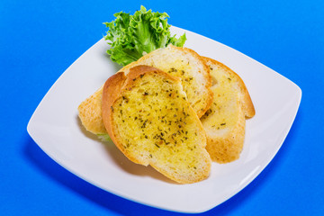 Garlic bread on black plate blue table