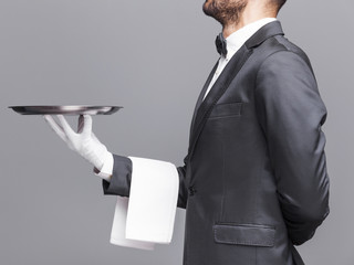 Cropped image of a waiter holding a silver tray on gray backgrou
