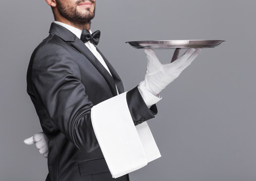 Butler Holding A Silver Tray On Gray Background