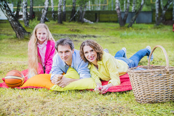 Fototapeta premium happy family mother, husband and daughter lying on the grass at a picnic