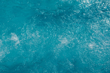 Blue water surface with sun reflection in swimming pool