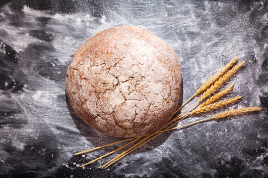 bread with wheat ears on dark board