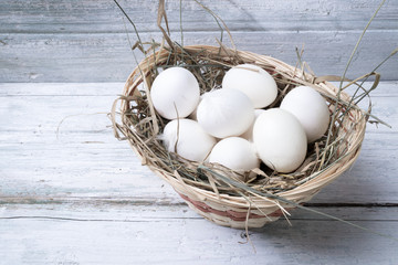 White chicken eggs in straw basket