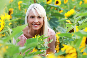 Hübsche blonde Frau mittleren Alters im Sonnenblumenfeld