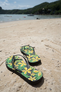 Flipflops on a sandy ocean beach over tropical landscape. Summer vacation concept