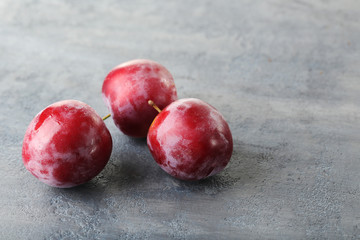 Fresh plums on a grey wooden table