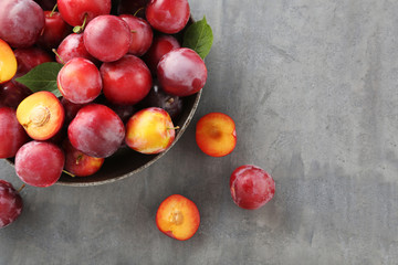 Fresh plums on a grey wooden table