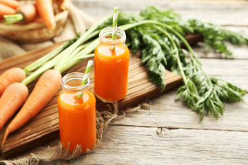 Fresh carrot juice in bottles on a grey wooden table