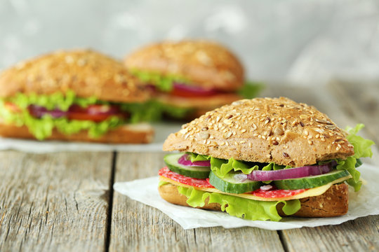 Tasty sandwiches with salami on a grey wooden background