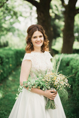 Bride. Beautiful young blond woman in the park with flower wreath and bouquet on a warm summer day