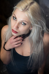 Junge Frau mit blonden Haaren trägt Halsband und schwarzes Kleid