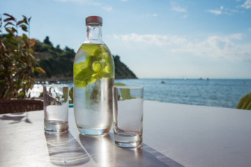 Bottle of cold mint water with two glasses on a table
