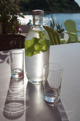 Bottle of cold mint water on a table with a sea on background