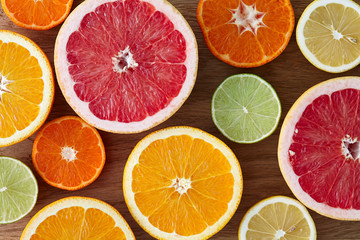 A mix of different citrus fruits cut in half, wooden background