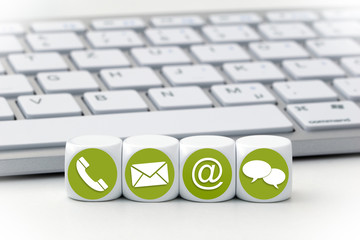 Website and Internet contact us page concept with green icons on cubes in front of a keyboard