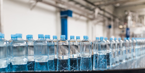 Water factory - Water bottling line for processing and bottling pure spring water into small bottles. Selective focus.