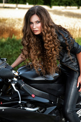 Fototapeta na wymiar Sexual biker woman wearing black leather jacket with her sport m