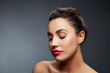 Portrait of young brunette girl with closed eyes and red lipstick over grey background