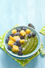 Breakfast green smoothie bowl topped with fruits