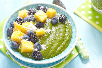 Breakfast green smoothie bowl topped with fruits