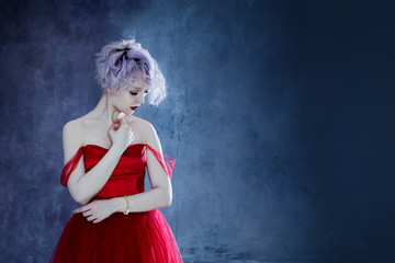 Fashion photo of young magnificent woman in red dress. Textured background