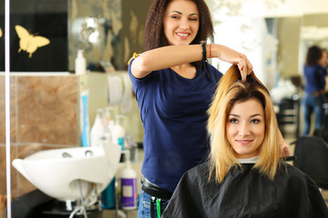 Female hairdresser hands holding comb and hair lock