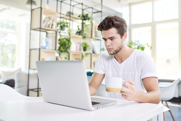 Coffee makes his day. Young handsome man drinking coffee and loo