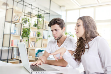 Two young business people in casual wear looking at the laptop.