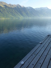 Wooden jetty on Brienzersee Lake, Switzerland on a sunny morning in late Spring, with Rothorn Mountain in the far distance 