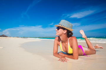 Fit woman in sun hat and bikini at beach