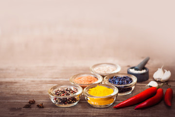 Spices for cooking meat: turmeric, chili pepper, barberry on the wooden table. Horizontal.