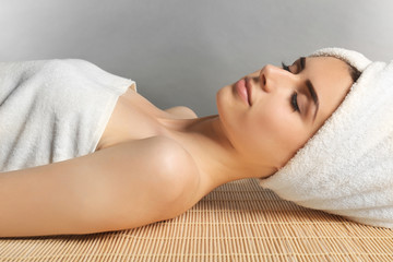 Obraz na płótnie Canvas Pretty woman with towel on hair lying on table