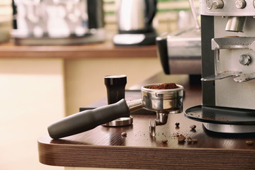 Portafilter with ground coffee on wooden table