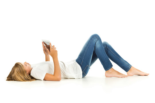 Young girl lying on the floor using tablet pc over white backgro