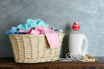 Clothes in wicker basket and detergent on table