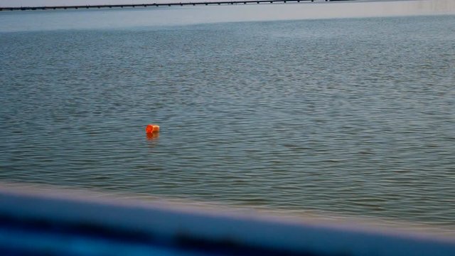 Ship sails close to orange buoy swinging on the waves