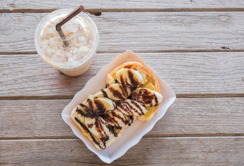 Chocolate banana toast in paper plate and cup of iced coffee on