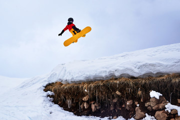 Snowboarder jumping from   springboard on a snowy hill with grass. © Аrtranq