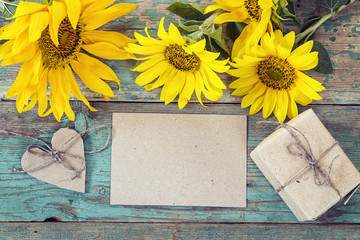 Background with empty card, sunflowers and gift box on old woode